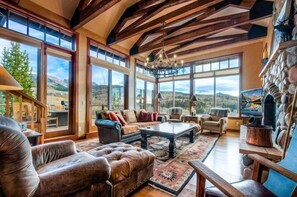 Un salón espacioso con ventanas amplias, chimenea y techo alto con vigas a la vista.