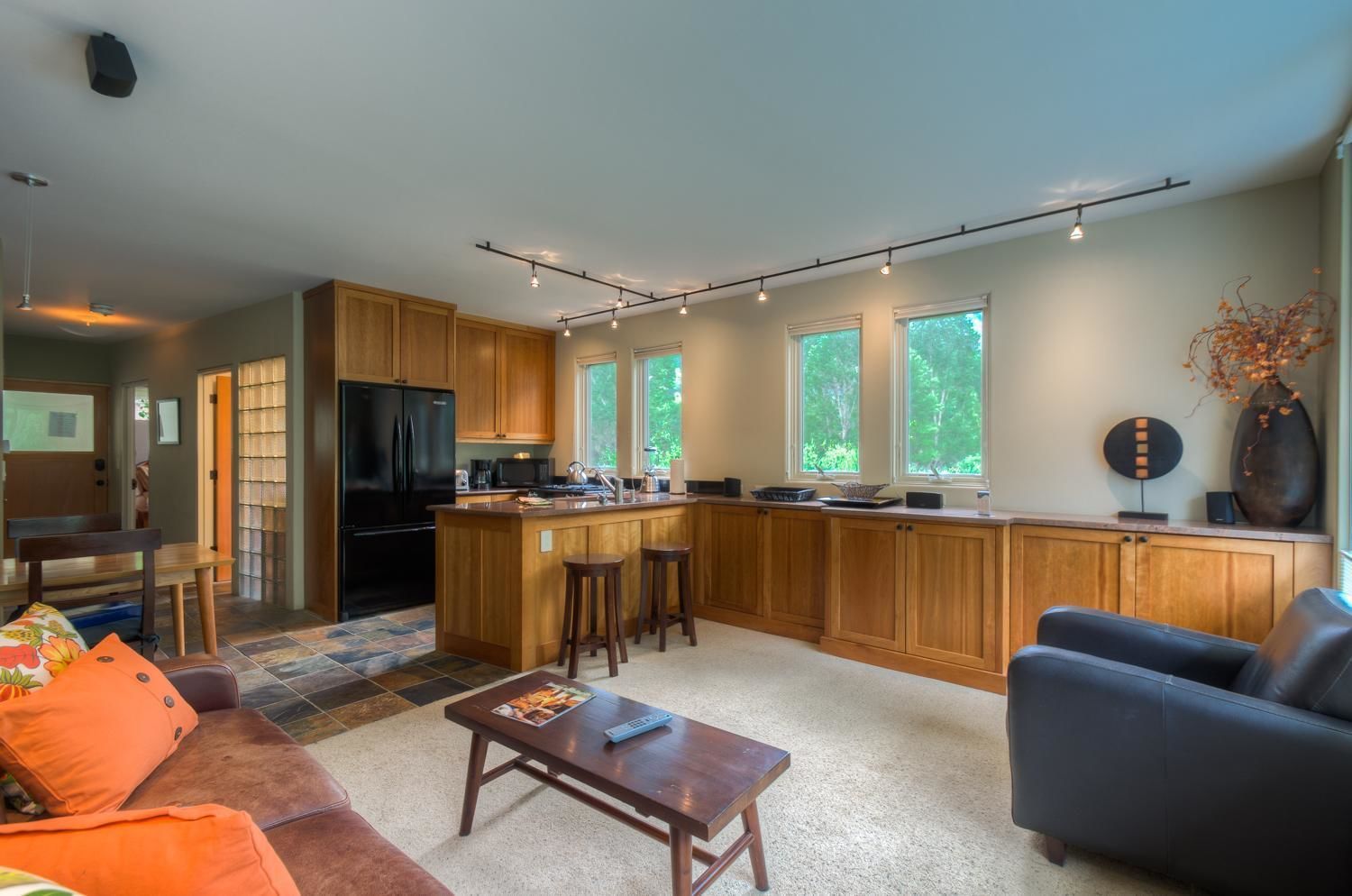 Une cuisine moderne avec des meubles en bois, un îlot central et un coin repas comprenant un canapé et une table basse.