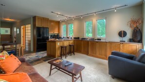 A modern kitchen with wooden cabinets, a central island, and a dining area with a sofa and coffee table. - Muscatel Flats 2 1 Bedroom Condo By Accommodations in Telluride (Telluride)