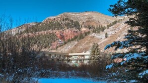 A building with a modern architectural style, situated near a body of water and surrounded by a mountainous landscape. - Muscatel Flats 2 1 Bedroom Condo By Accommodations in Telluride (Telluride)