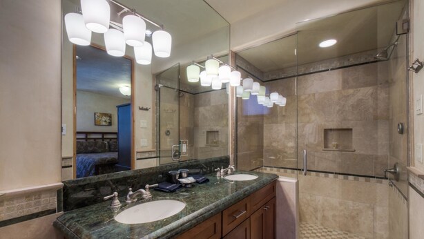 Une salle de bain moderne avec deux lavabos, un grand miroir et une douche à parois de verre.