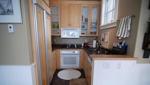 Een compacte keuken met houten kastjes, een magnetron, een oven en een klein aanrecht.