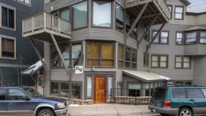 A multi-story building with a prominent wooden front door, multiple balconies, and large windows. - Plunge H 3 Bedroom Condo By Accommodations in Telluride (Telluride)