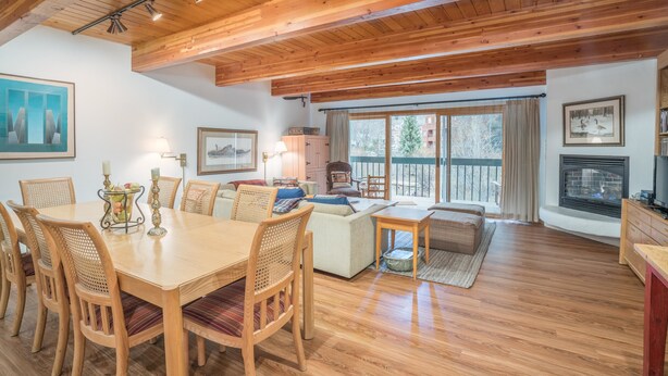 Un vaste espace de vie doté d’un plafond en bois, d’une table à manger avec des chaises, d’un canapé et d’une cheminée.