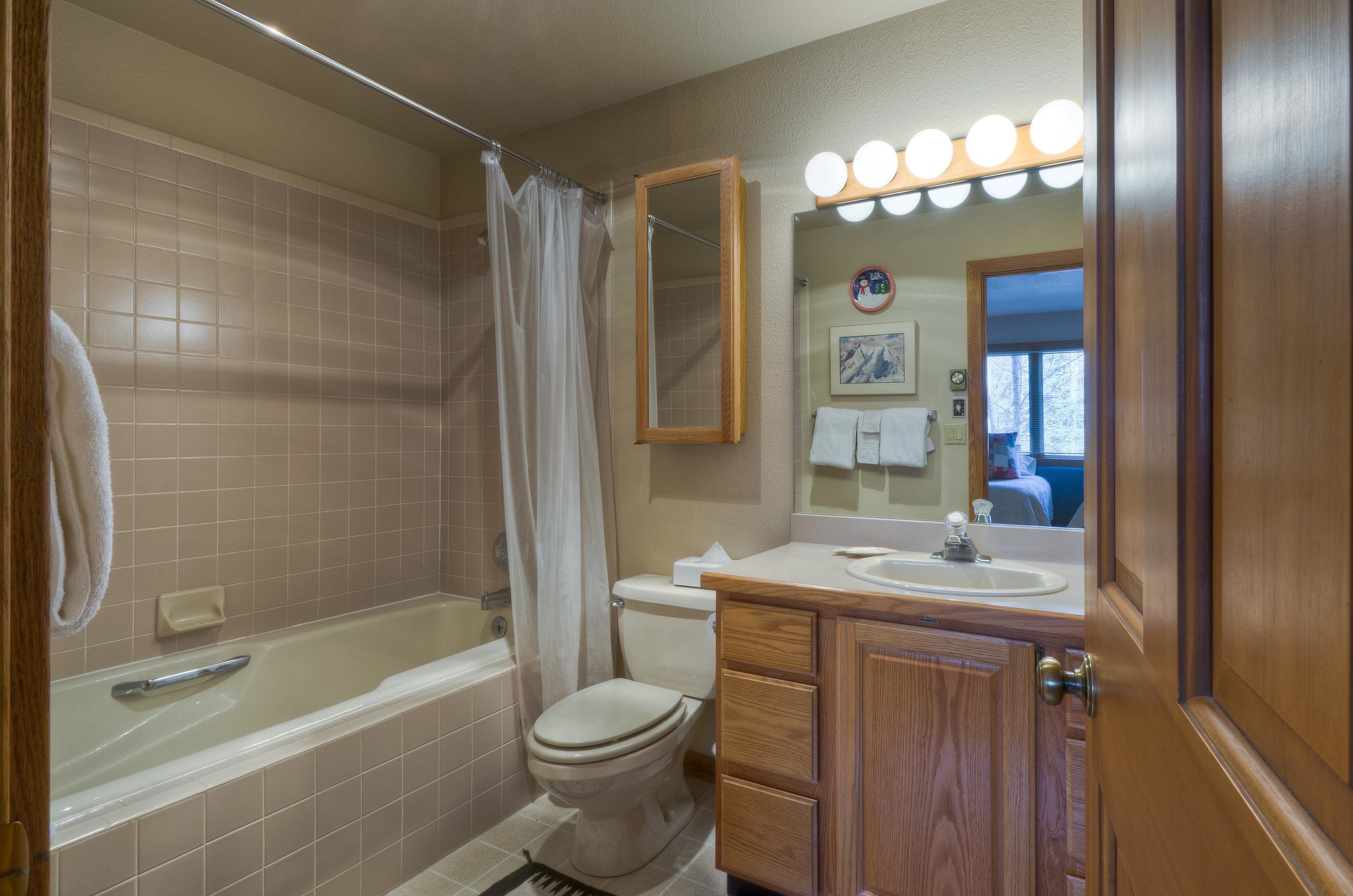 A bathroom with a bathtub, toilet, vanity with a mirror, and a sink.