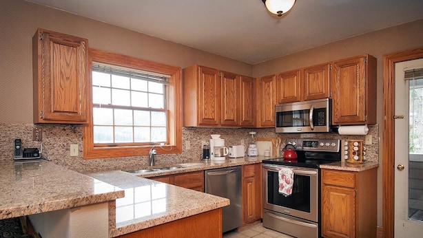 A kitchen with wooden cabinets, granite countertops, a microwave, a stove, and a coffee maker. - Sundance 302 2 Bedroom Condo By Accommodations in Telluride (Telluride)