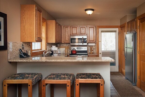 Enjoy cooking in this well-equipped kitchen with a central island, stainless steel appliances, and ample workspace.