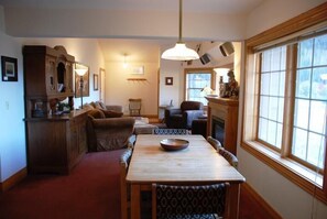Cozy living room with a dining area, featuring a dining table, patterned chairs, and a fireplace.