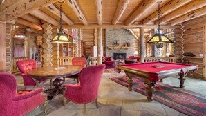 A log cabin interior with a pool table, red upholstered chairs, a fireplace, and a stone wall. - Rocky Road Retreat 4 Bedroom Holiday home By Accommodations in Telluride (Telluride)