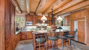 A spacious kitchen with wooden cabinets, a large island with bar stools, and a stone floor. - Rocky Road Retreat 4 Bedroom Holiday home By Accommodations in Telluride (Telluride)