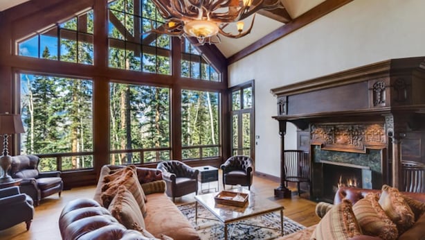 A spacious living room with large windows, leather sofas, a fireplace, and a chandelier. - Timber Creek 10 Bedroom Holiday home By Accommodations in Telluride (Telluride)