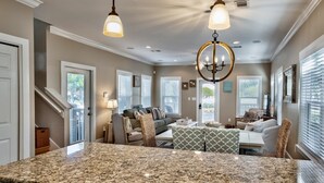 A spacious living area with a kitchen island, a dining table, and a seating area with multiple chairs.