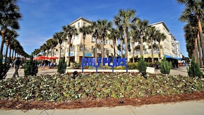 A hotel with a 'CIFLEPLACE' sign, palm trees, and a pedestrian walkway.