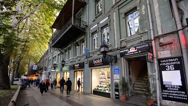 Una calle con tiendas y la entrada de un hotel.
