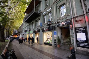 Une rue bordée de boutiques et l’entrée d’un hôtel.