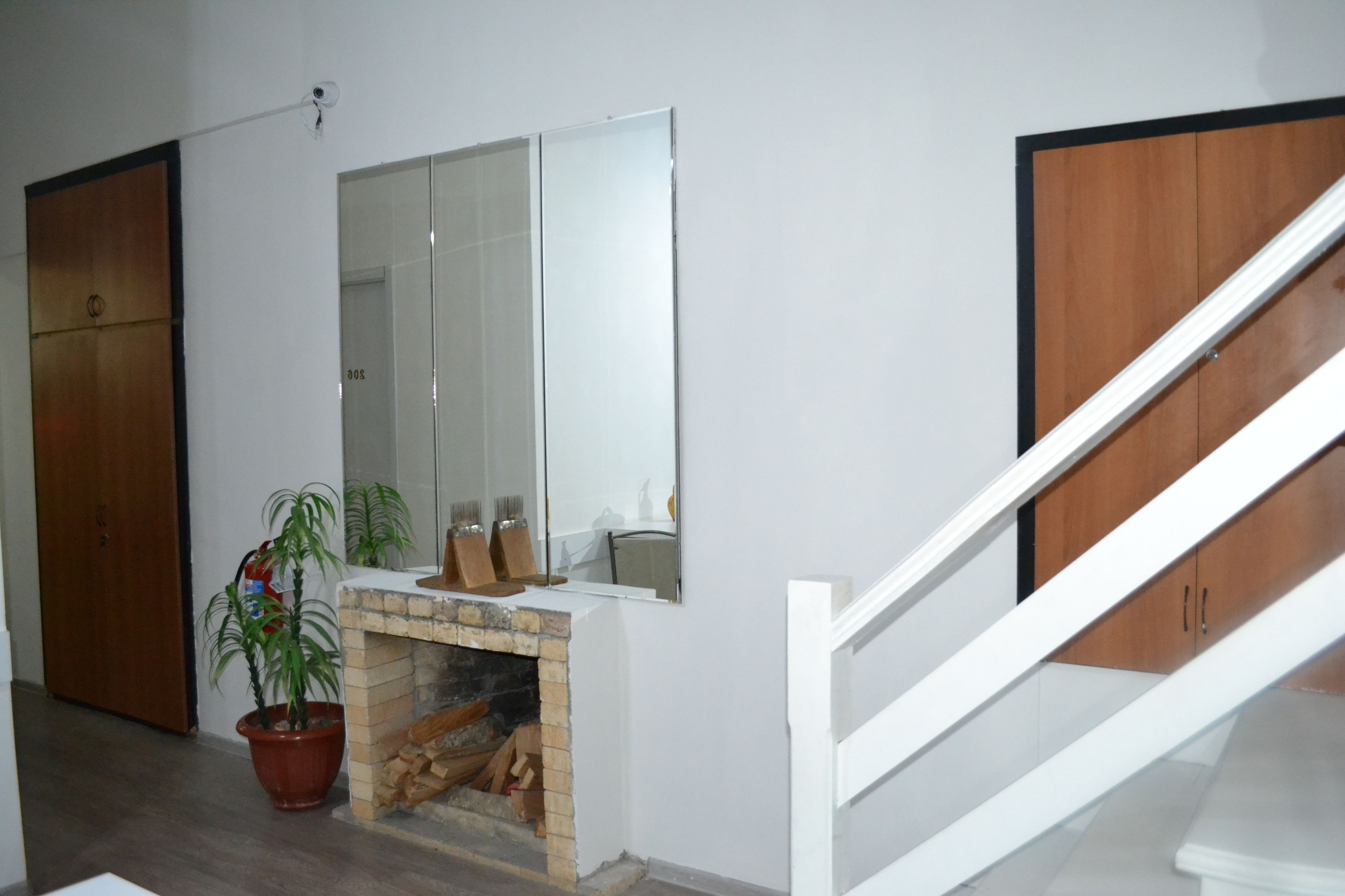 A room with a fireplace, a mirror, a wooden door, and a staircase.