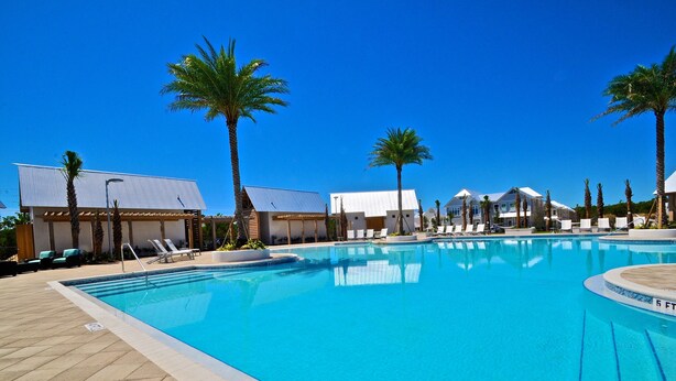 A swimming pool with lounge chairs and palm trees.