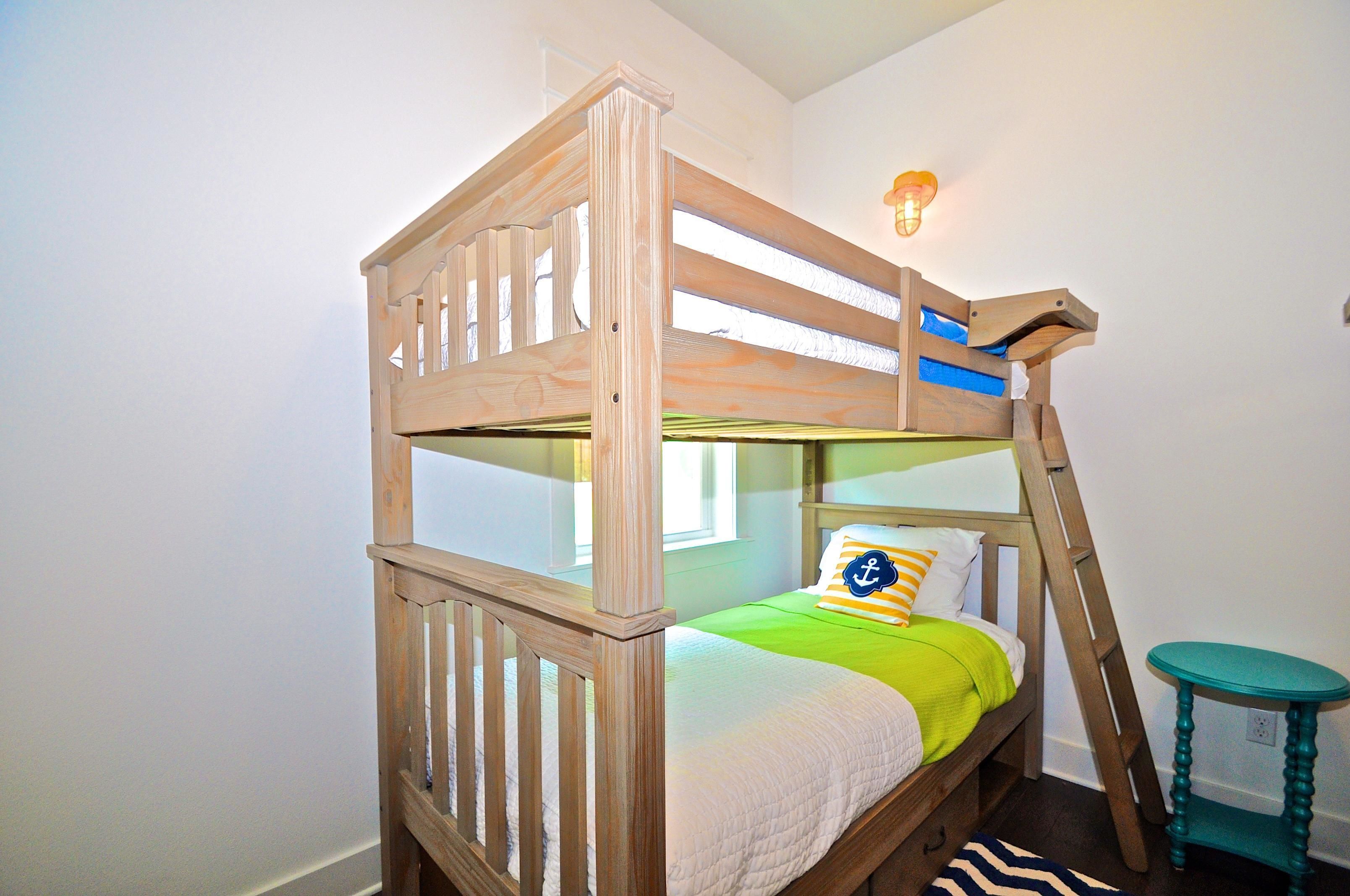 Una cama litera con estructura de madera, un edredón verde y una almohada con un diseño de ancla.