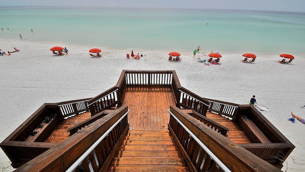 A wooden boardwalk leading to a beach with red umbrellas and lounge chairs. - Redfish Village M2 417 3 Bedroom Condo By Coastal Dreamin (Santa Rosa Beach)