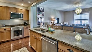 A modern kitchen with wooden cabinets, stainless steel appliances, and a large island with a sink. - Redfish Village M2 417 3 Bedroom Condo By Coastal Dreamin (Santa Rosa Beach)
