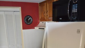 A compact kitchen with a white refrigerator, a microwave, a stove, and a clock on the wall. - Cove II 832F 2 Bedroom Condo By Midnight Cove II (Siesta Key)