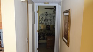 A narrow hallway with a carpet, a door leading to a bedroom, and a framed picture on the wall. - Cove II 832F 2 Bedroom Condo By Midnight Cove II (Siesta Key)