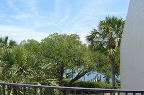 A balcony with a view of a lake and palm trees. - Cove II 832F 2 Bedroom Condo By Midnight Cove II (Siesta Key)