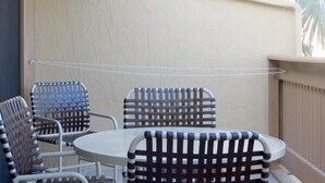 A patio with a round table and four chairs with a lattice backrest design. - Cove II 833F 2 Bedroom Condo By Midnight Cove II (Siesta Key)