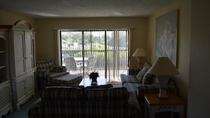 A living room with a sofa set, a coffee table, a lamp, and a painting on the wall. - Cove II 922C 2 Bedroom Condo By Midnight Cove II (Siesta Key)