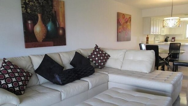 A modern living room with a sectional sofa, a coffee table, and a dining area with a glass table and chairs.