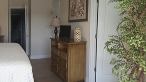 Un dormitorio ordenado con cama, mesitas de noche, cómoda y espejo.
