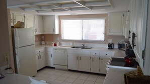 A kitchen with white cabinets, a refrigerator, a dishwasher, a toaster, and a window with blinds. - Cove II 934C 2 Bedroom Condo By Midnight Cove II (Siesta Key)