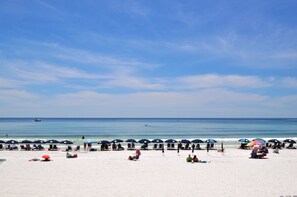 A beach with rows of umbrellas and beach chairs, a clear sky, and the ocean in the background. - Sandestin Vacation Rental by Coastal Dreamin (Miramar Beach)