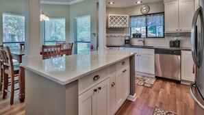 A modern kitchen with a central island, stainless steel appliances, and a dining area with wooden chairs.