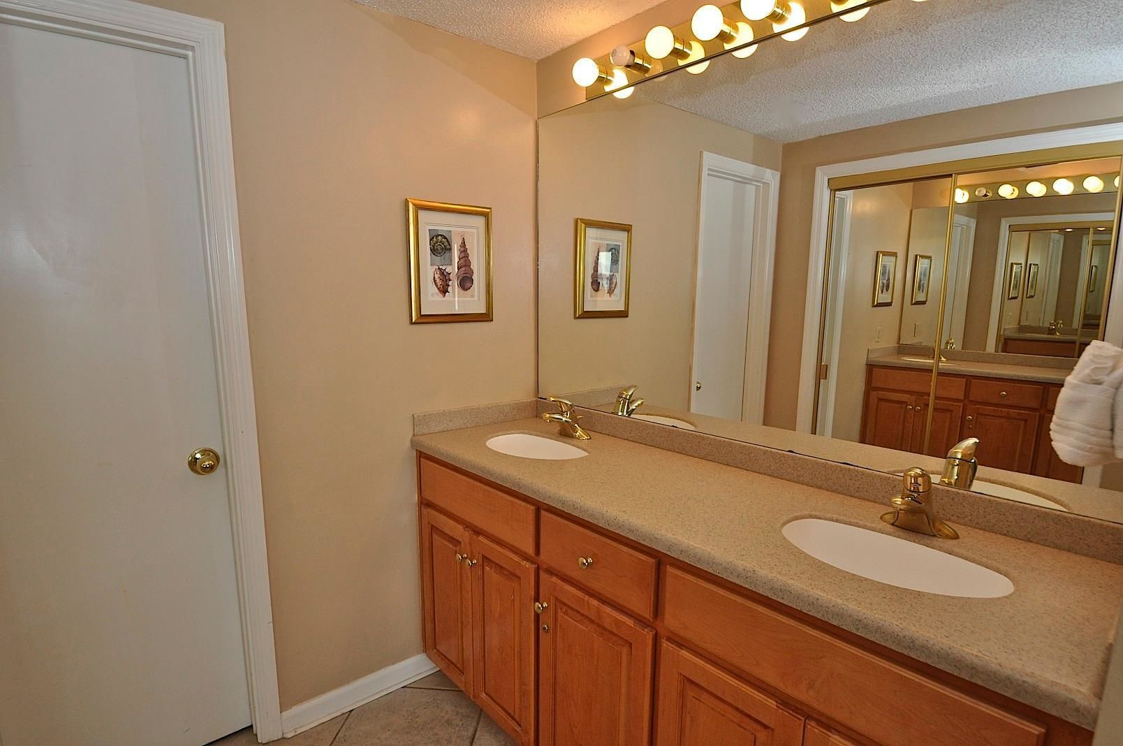 A bathroom with two sinks, wooden cabinets, a large mirror, and wall-mounted lights.