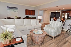 Un salon comprenant un canapé, un fauteuil, une table basse et un coin repas avec des chaises et une table.