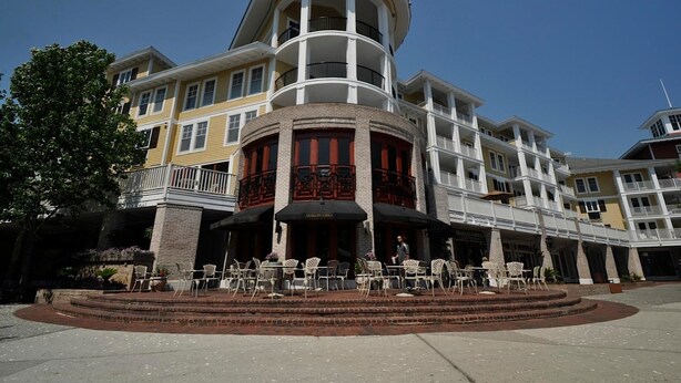 A multi-story hotel with a central courtyard, outdoor seating area, and a prominent circular tower. - Observation Point 456 1 Bedroom Condo By Coastal Dreamin (Miramar Beach)