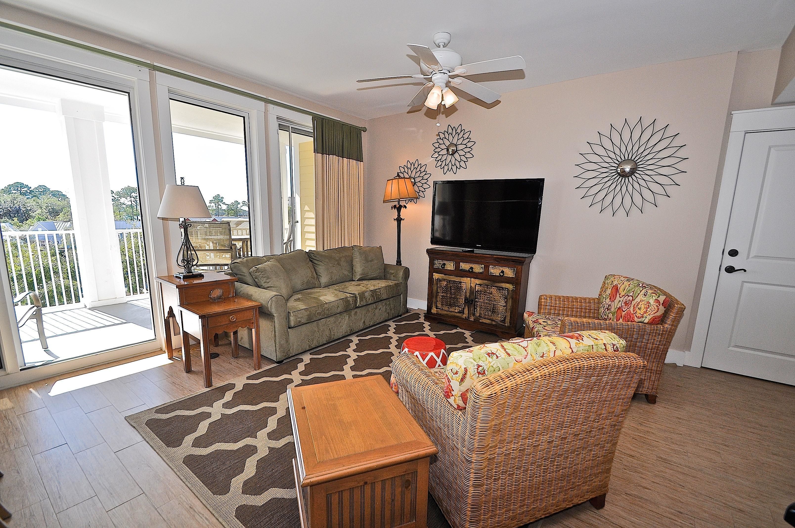 A living room with a sofa, armchair, TV, and decorative wall art.