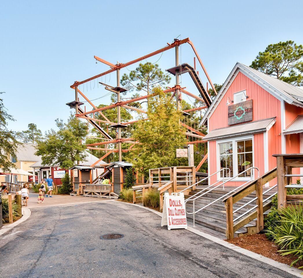 A rustic building with a red exterior and a sign advertising dolls, doll clothes, and accessories.