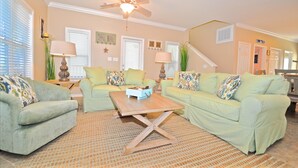 A living room with two light green sofas, a wooden coffee table, and a ceiling fan. - Old Florida Village Sea Psalm 4 Bedroom Holiday Home By Coastal Dreamin (Santa Rosa Beach)