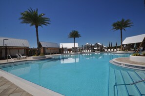 Una piscina con sillas de descanso y palmeras.