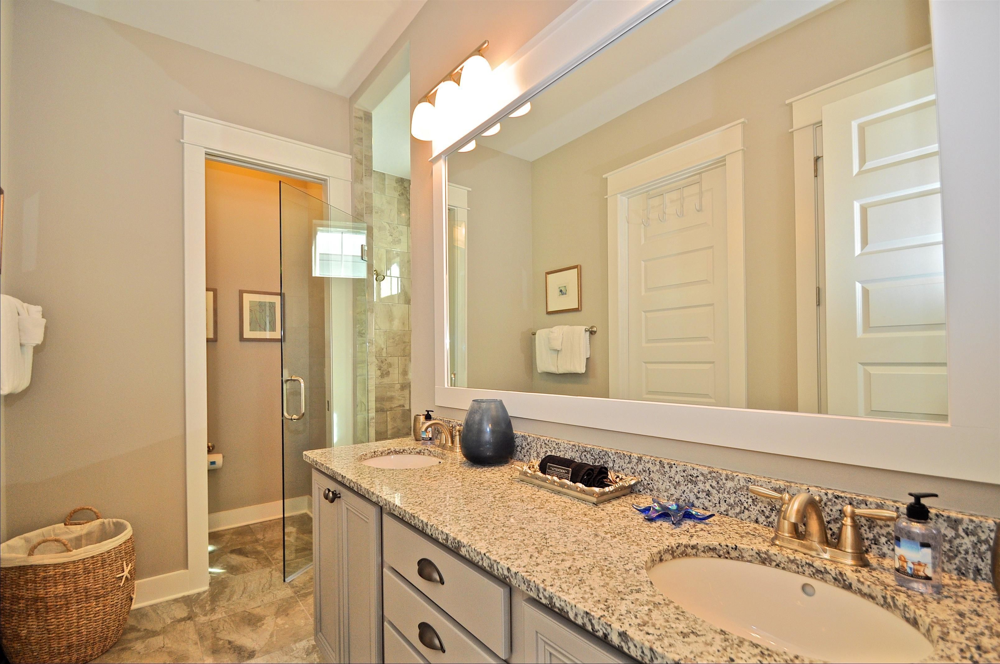 A bathroom with two sinks, a large mirror, and a shower area.