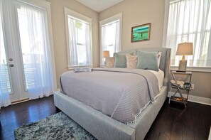 Un dormitorio con cama, una mesita de noche con lámpara y una ventana con cortinas.
