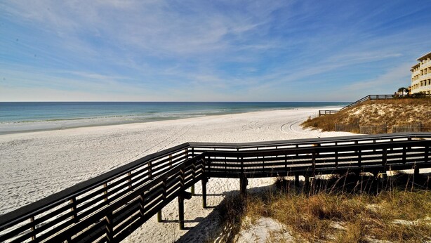 A beach with a wooden walkway leading to a building with a balcony overlooking the ocean. - Six Palms Dreamin 2 Bedroom Condo By Coastal Dreamin (Santa Rosa Beach)