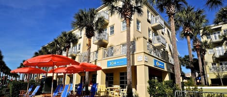 Ein Hotel mit Außenbestuhlung, Palmen und blauem Himmel.