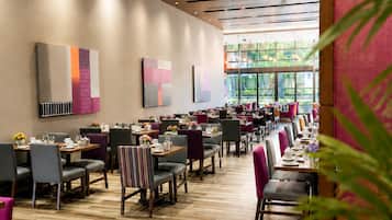Un restaurante espacioso con varias mesas y sillas, ventanas amplias y decoración moderna.
