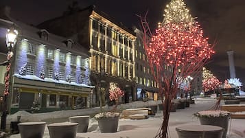 Una calle nevada con edificios iluminados y un árbol decorado.