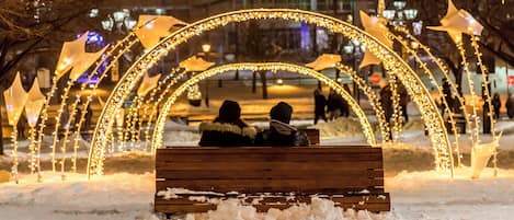 Um banco em um cenário nevado, com arcos e árvores iluminados.