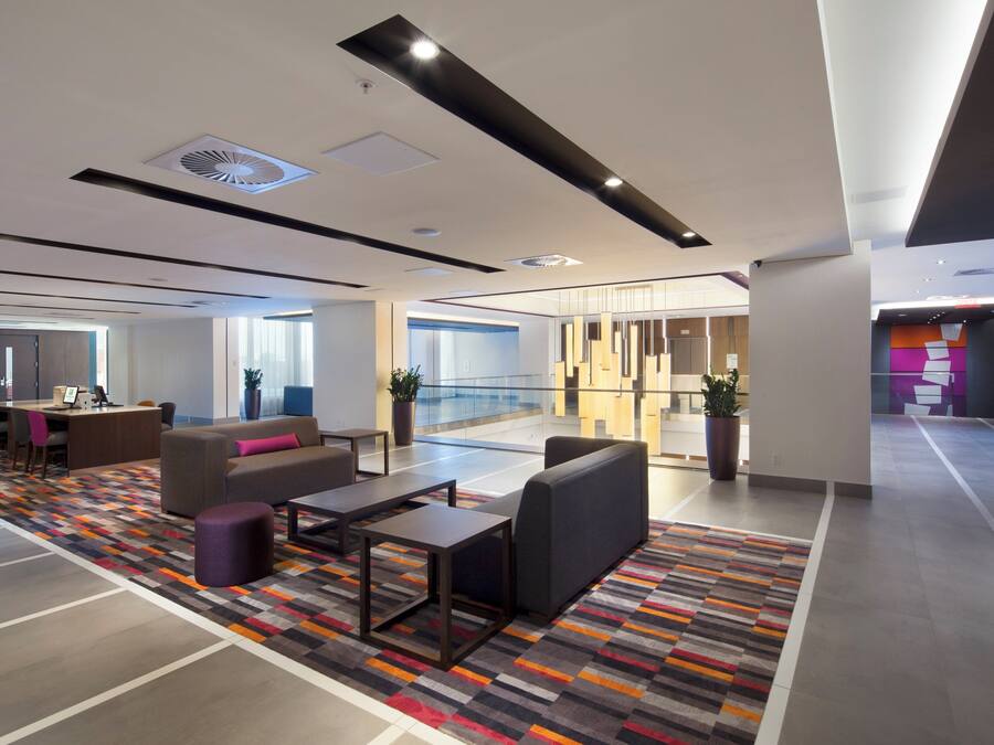 Een moderne lobby met zithoeken, een receptiebalie en een glazen scheiding.
