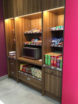 A self-service snack and beverage kiosk with various packaged goods and a microwave. - Holiday Inn Hotel & Suites Montreal Centre-ville Ouest by IHG (Montreal)